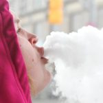 Person exhaling vapor clouds in winter clothing
