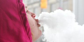 Person exhaling vapor clouds in winter clothing