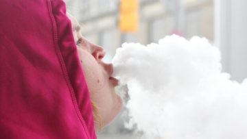 Person exhaling vapor clouds in winter clothing