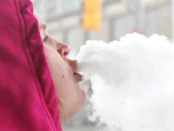 Person exhaling vapor clouds in winter clothing