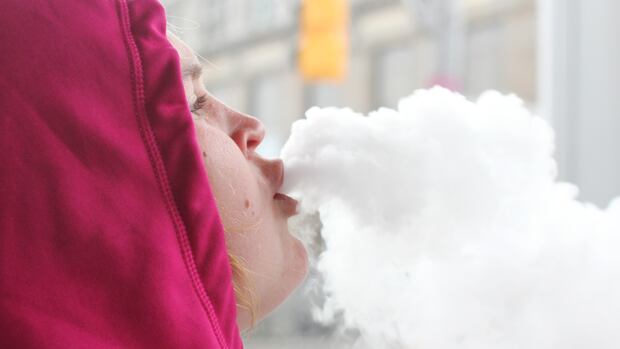 Person exhaling vapor clouds in winter clothing