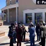 Group gathered outside historic building with statues.
